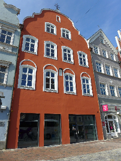Prächtige rote Stadthausfassade mit historischen Fenstern.